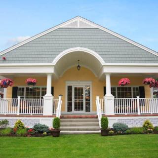 A charming house with a front porch, colorful flowers, and a well-maintained lawn.