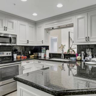 A modern kitchen with white cabinets and granite countertops, featuring stainless steel appliances.