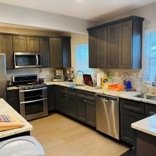 A modern kitchen with dark wood cabinets and stainless steel appliances.