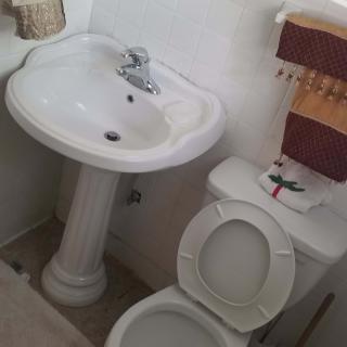 Compact bathroom with a sink and toilet alongside a towel rack.