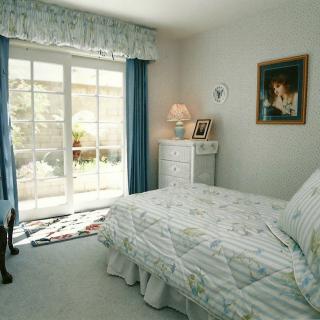 A cozy bedroom with a bed, lamp, and sliding glass door.