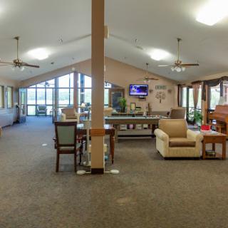 A spacious community lounge featuring comfortable seating, a pool table, and large windows allowing natural light.