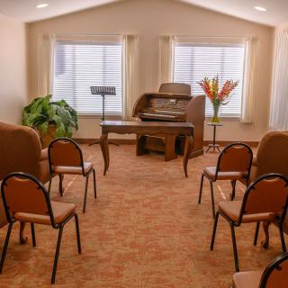 A small chapel interior with an organ, chairs, and windows allowing natural light.