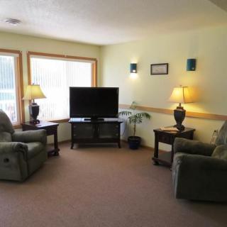 A cozy living room featuring armchairs, a television, and decorative lamps.