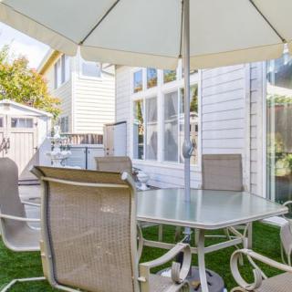 A cozy outdoor patio setup with a glass table and chairs under a large umbrella.