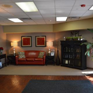 A cozy lobby area featuring a red couch, decorative lamps, and a bookshelf.