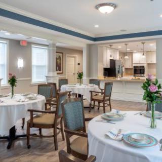 An elegant dining room setup with tables adorned with floral centerpieces.
