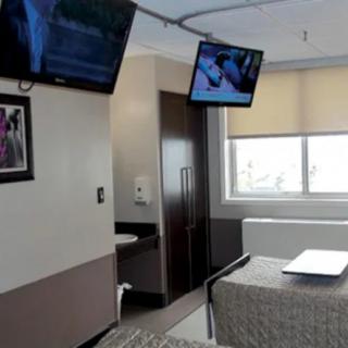 A modern hospital room with two televisions and a window.