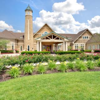 A beautifully designed residence featuring a charming facade and well-maintained gardens under a bright sky.