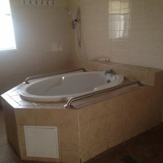 A tiled bathroom featuring a whirlpool bathtub set in an elevated platform.