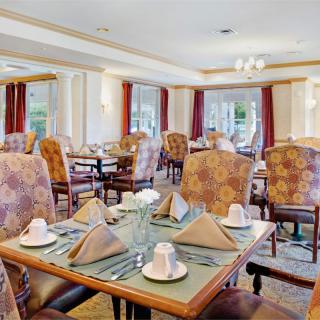 An elegantly set dining room with neatly arranged tables and chairs, ready for guests.