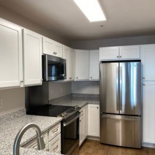 A modern kitchen with white cabinets and stainless steel appliances.