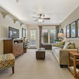 A cozy and thoughtfully decorated living room with a sofa, artwork on the walls, and a ceiling fan.