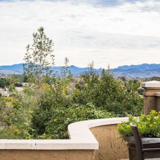 A scenic view from a balcony overlooking lush greenery and distant mountains.