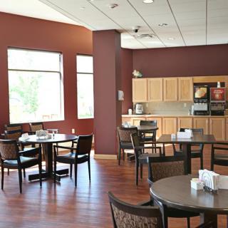A modern cafeteria with tables, chairs, and a kitchenette.