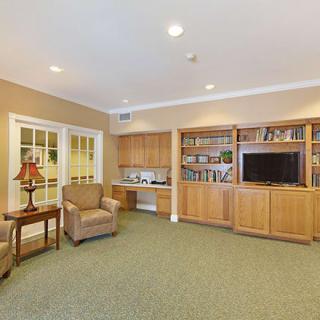 A cozy living room with a TV, bookshelves, and comfortable seating.