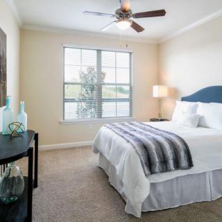 A neatly arranged bedroom with a large window, ceiling fan, and elegant decor.