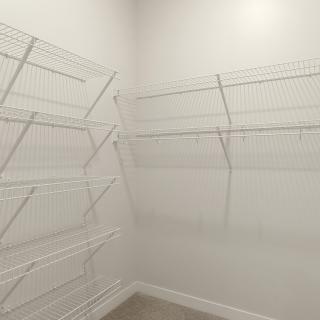 An empty closet with white wire shelving and white walls.