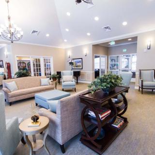 A spacious and elegantly designed living room with comfortable sofas, tasteful decor, and a chandelier.