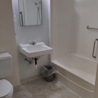 A minimalist bathroom with a sink, toilet, and bathtub.
