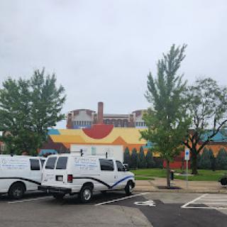 A parking lot scene featuring white vans and a colorful building in the background on a cloudy day.
