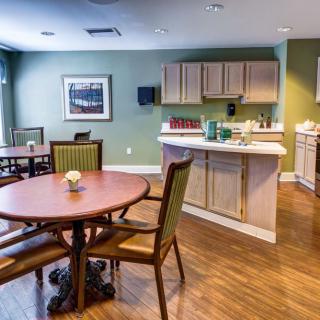A modern dining and kitchen area featuring wooden flooring, tables, and chairs.