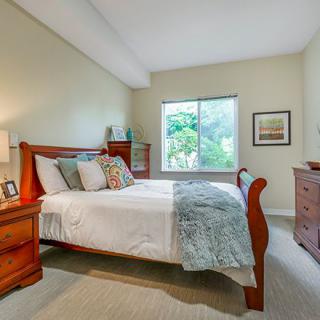 A cozy bedroom with wooden furniture and a large window.