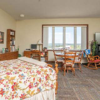 A cozy bedroom with floral bedding and ample natural light from a large window.