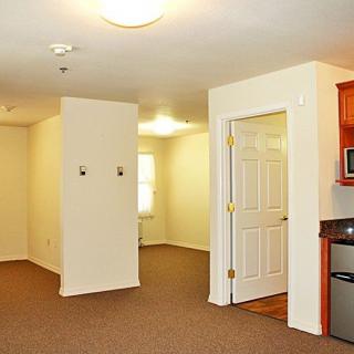 An empty apartment with a small kitchen and open living space.
