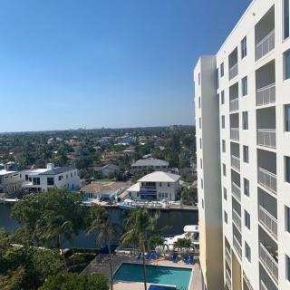A view from a balcony overlooking a swimming pool and residential buildings on a clear day.