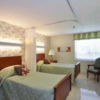 A hospital room with two beds, separated by a curtain divider.
