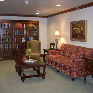 A traditional living room with elegant furnishings, including a sofa, armchair, coffee table, and bookcase.