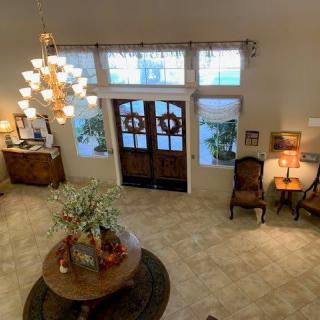 A spacious and elegantly decorated foyer with a chandelier, wooden doors, and stylish furniture.