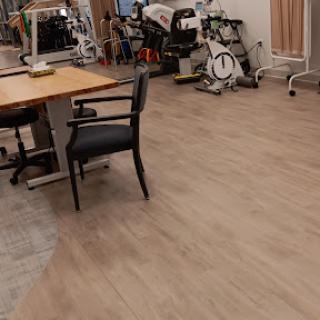 A spacious rehabilitation office featuring wooden floors and exercise equipment.