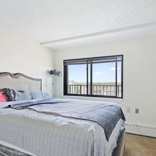 A bright and airy bedroom featuring a neatly made bed with a large window providing natural light.