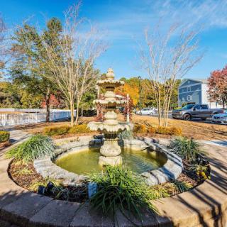 A beautiful garden fountain surrounded by colorful autumn foliage under a clear blue sky.