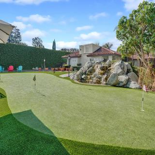 A beautifully landscaped residential putting green with artificial turf.