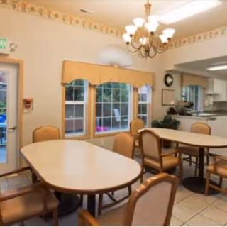 A cozy dining area with tables, chairs, and a view into the kitchen.