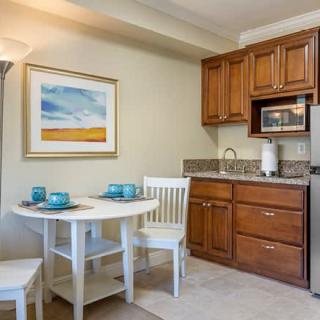A cozy kitchenette with wooden cabinets, a small dining table, and modern appliances.