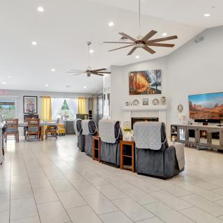 A spacious and modern living room with a contemporary design, featuring comfortable seating, a ceiling fan, a television, and a fireplace.