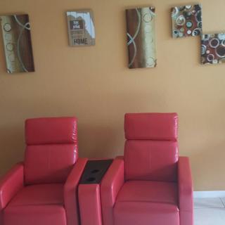 A modern living room setup featuring two red chairs and decorative wall art.