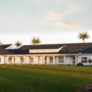A white house with a large lawn and palm trees, set against a sunset sky.