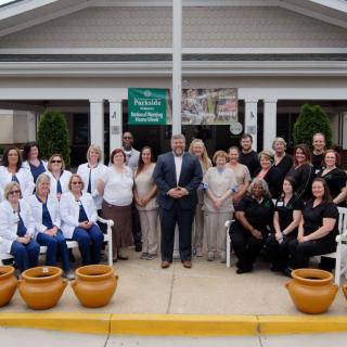 A group of medical staff posing for a photo in front of a building entrance.
