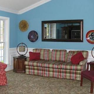 A cozy living room with a plaid sofa, armchair, and decorative plates on the walls.