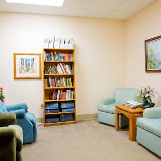 A cozy waiting room featuring comfortable seating and a bookshelf filled with various reading materials.