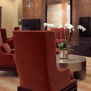 A modern lounge area with vibrant red chairs and a central silver table adorned with orchids.