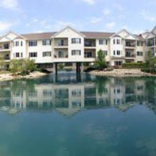 A residential apartment building reflected in a calm lake.