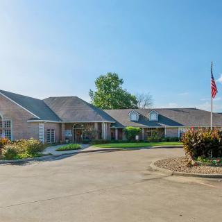 A sunny view of a building with a driveway and flag.
