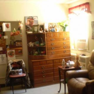 A cozy living room with a dresser, bookshelf, and comfortable seating arrangement.