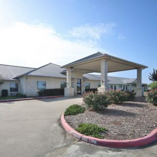 Front view of a building with a covered entrance and landscaped surroundings.